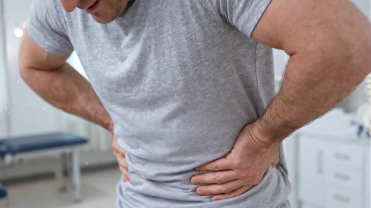 Person holding painful side and lower back over gray shirt in close view