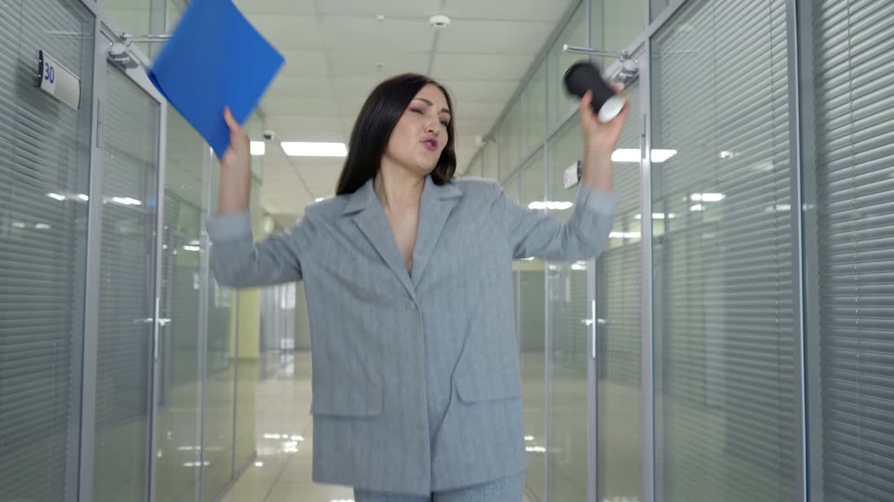 Joyful manager in grey jacket walks along hall dancing