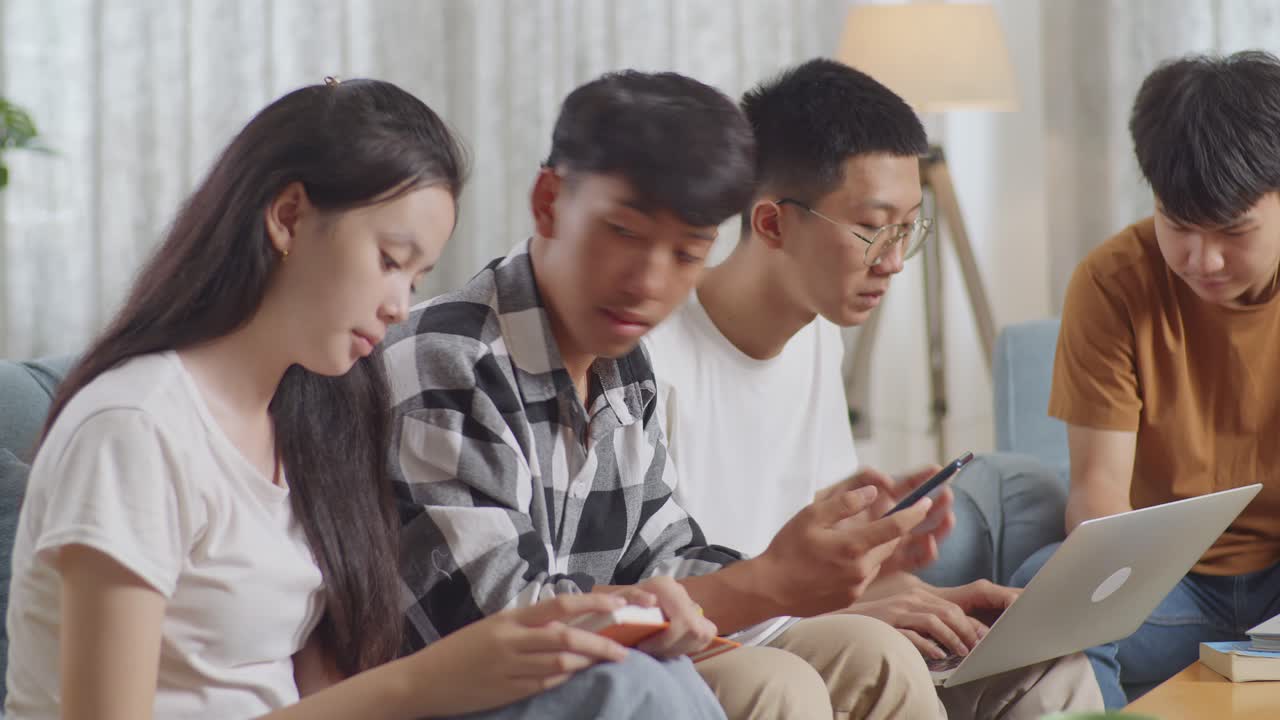 Tampilan Dekat Kelompok Remaja Asia Belajar di Rumah. Siswa dengan Buku dan Laptop Melihat Smartphone, Merayakan Keberhasilan Proyek, dan Melakukan Tos