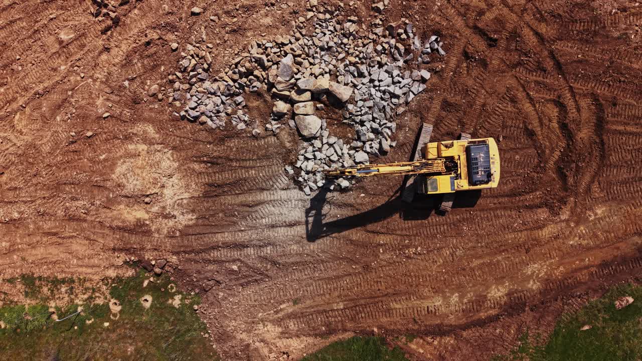 Maquinaria pesada retira rocas en una obra de construcción durante el día.
