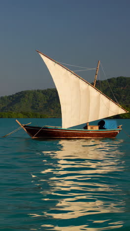 traditional wooden dhow sailing boat on calm water