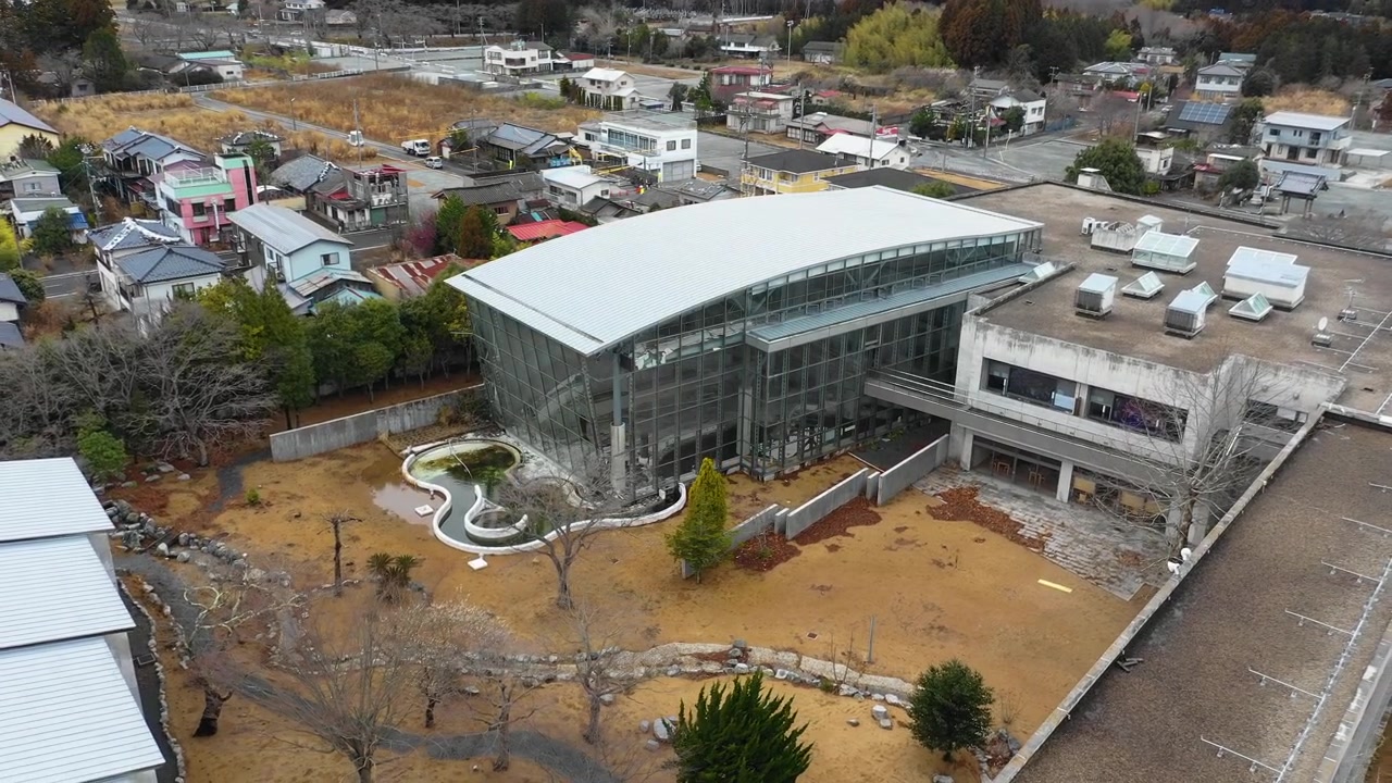 An aerial view reveals a glass building complex with a courtyard in Tomioka.