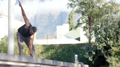 Afroamerikanischer-Mann-Beim-Fitnesstraining-An-Deck-Im-Sonnigen-Garten,-Zeitlupe