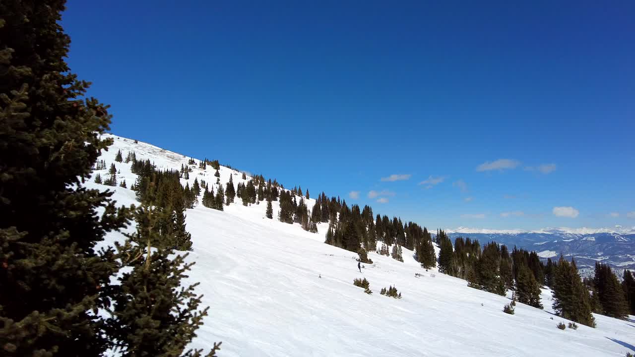 Person skiing down slopes at Breckenridge resort on beautiful sunny day