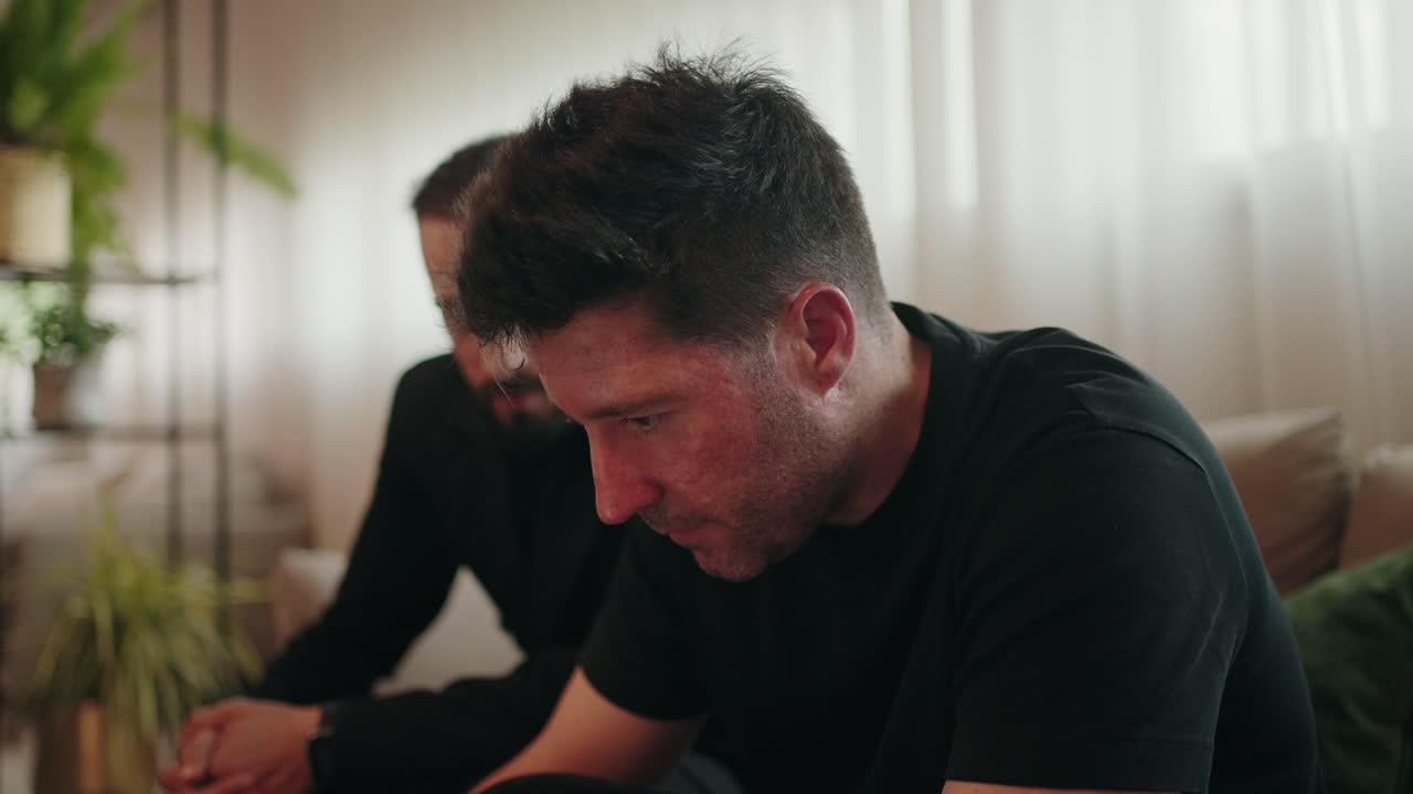 one man enters and sits quietly beside another in a moment of shared silence