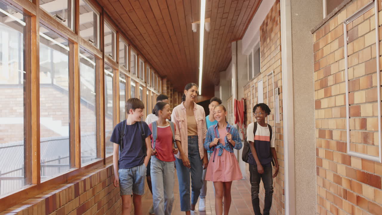 Walking in school hallway, teacher and students smiling and talking together