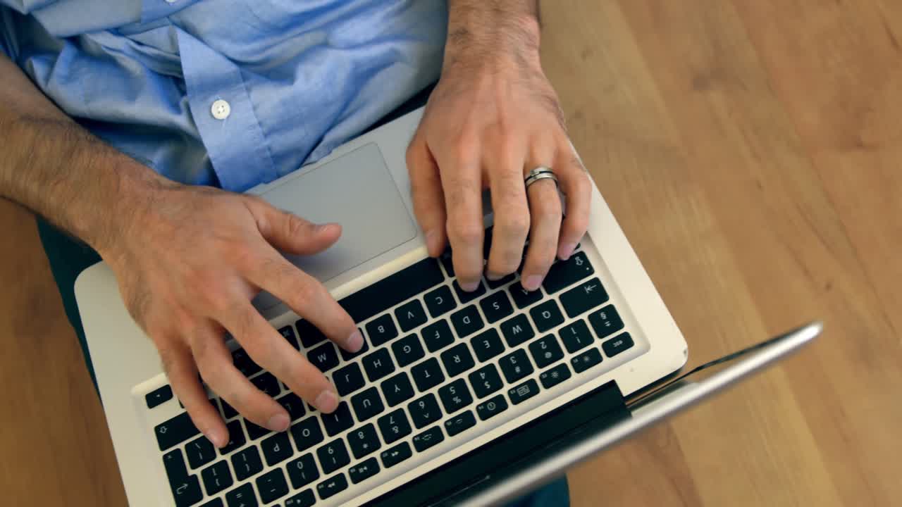 sección media de un hombre sentado en el suelo y usando una computadora portátil