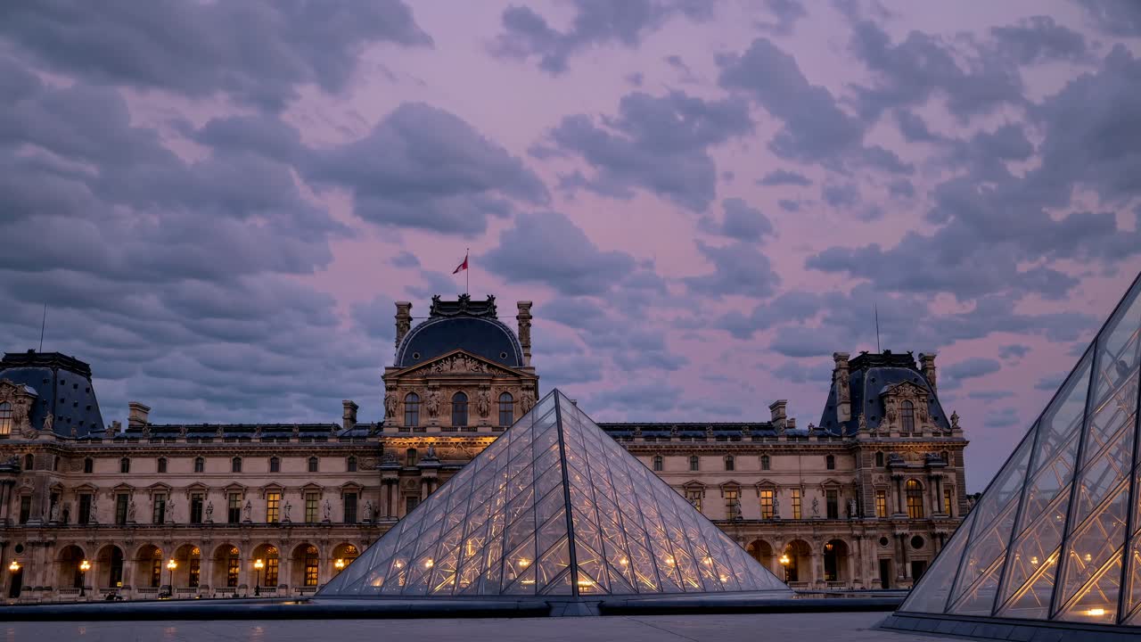 Wide-angle shot of the Louvre at dusk, showcasing its iconic glass pyramid and historic architecture