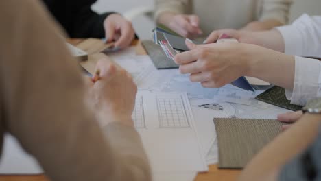 a collaborative design meeting in action, with team members selecting materials and colors, consulting floor plans, and engaging in creative decision-making for an interior design project.