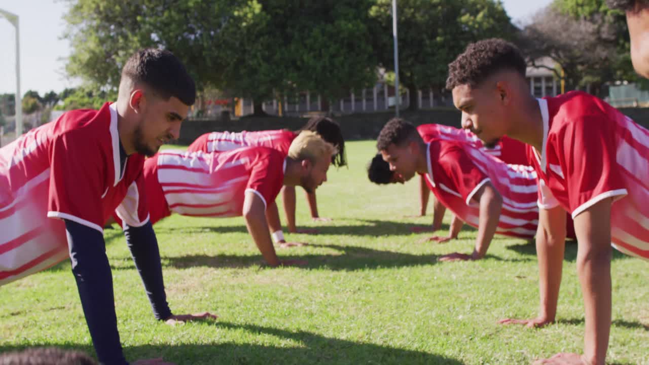 남성 축구 선수 들 의 다양한 그룹 이 운동장 에서 워밍업 하고 있으며, 푸시업 을 하고 있다