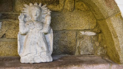 small intricate marble carved statue of religious figure in recessed stone holding area