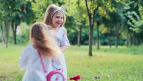 cute little kids girls in the park are jumping holding hands. cheerful children play on the grass near the trees