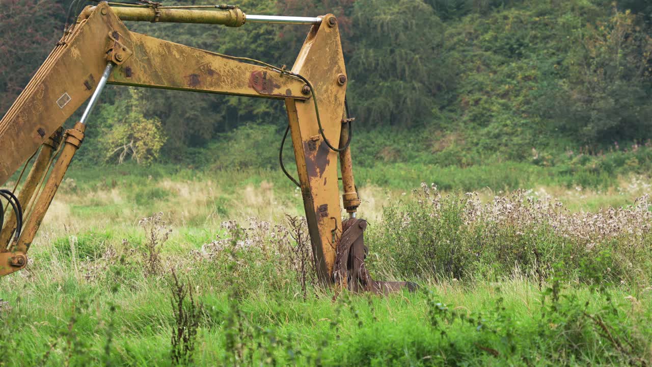 vieja excavadora amarilla abandonada oxidando en un campo, campo inglés, en 4k