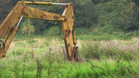 Old-abandoned-yellow-digger-rusting-in-a-field,-English-countryside,-in-4K