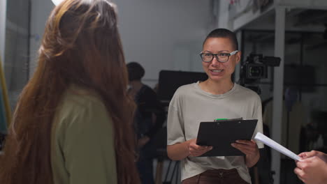 Film-Director-Talking-With-Male-And-Female-Actors-Holding-Scripts-Rehearsing-For-Shooting-Movie-Or-Video-In-Studio-7