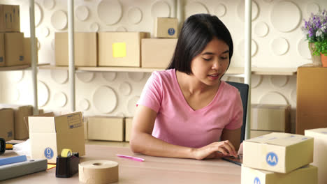 Asian-Women-business-owner-working-at-home-with-packing-box-on-workplace