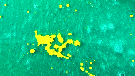 abstract splashes of yellow paint on green surface