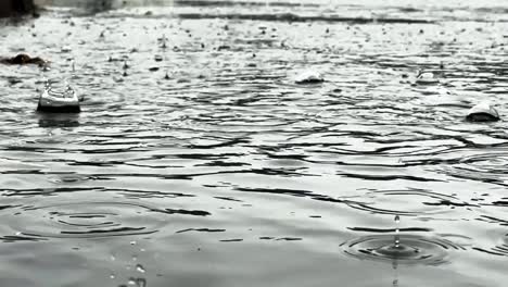 Slow-motion-shot-of-heavy-rain-water-falling-into-a-puddle-making-ripple