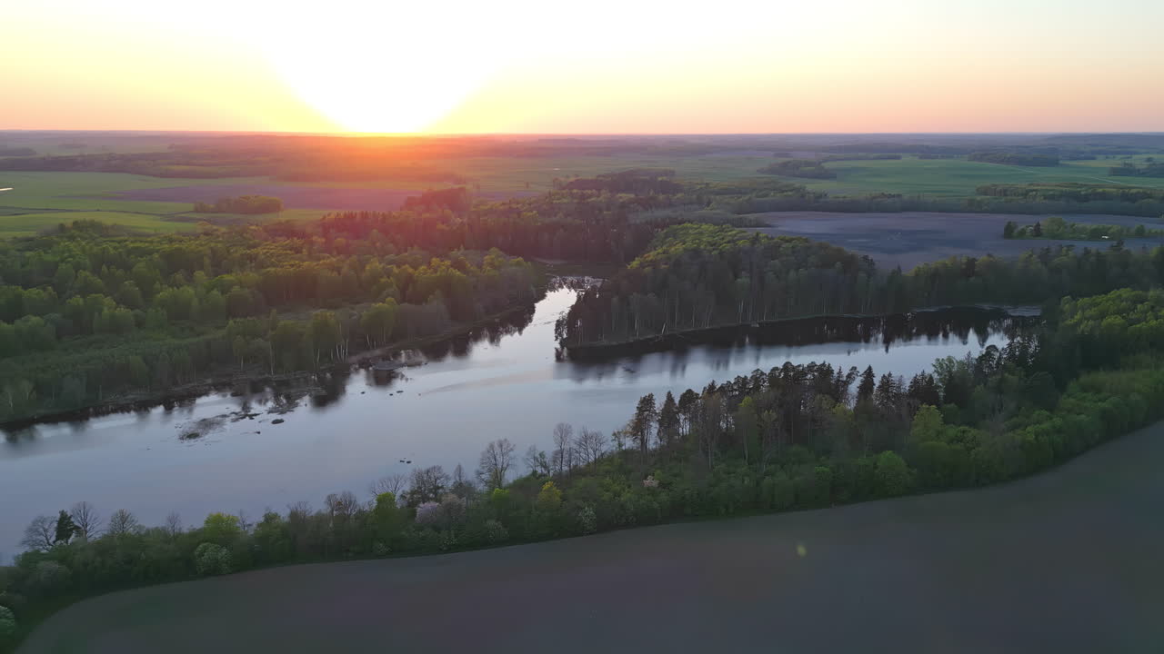 Un'inquadratura fluida al tramonto di un affluente, accanto a un paesaggio verde con una foresta