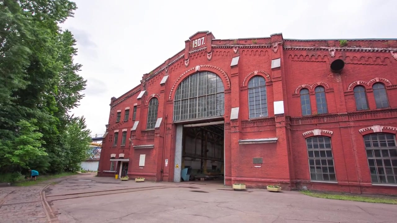 Stará cihlová tovární budova s okny a vraty, časosběr, hyperlapse. Čelní pohled na historickou dílenskou budovu v průmyslové zóně velkého závodu.