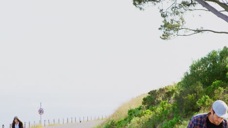 Front-view-of-cool-young-caucasian-skateboarders-skating-on-downhill-at-countryside-4k