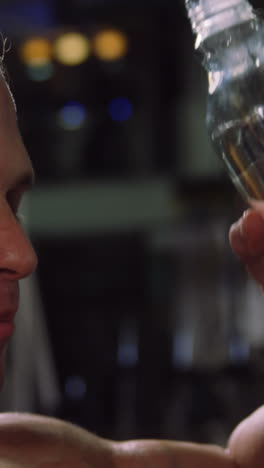 hombre musculoso bebiendo agua de una botella