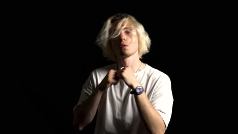 a blond, long-haired man threatens fighting, black background