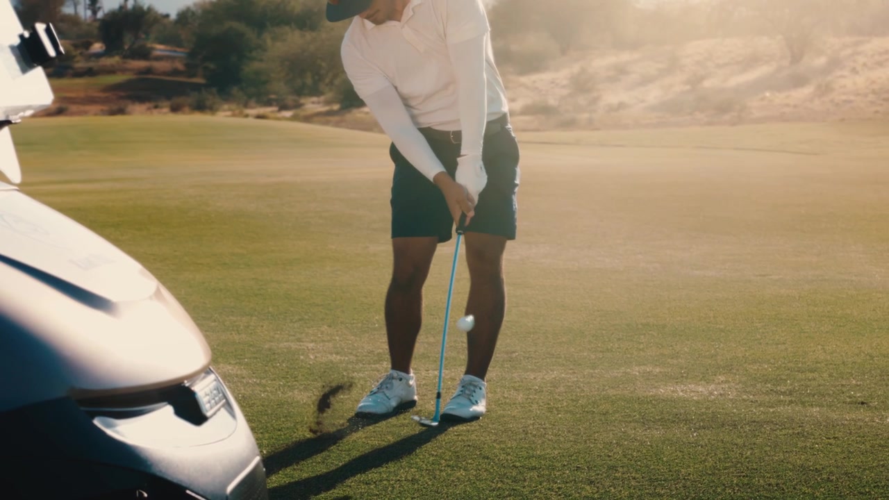 Scratch golfer hits wedge toward the green with perfect glowing divot on desert mountain course at sunset, captured in slow motion, suited to short-game tips and resort marketing.