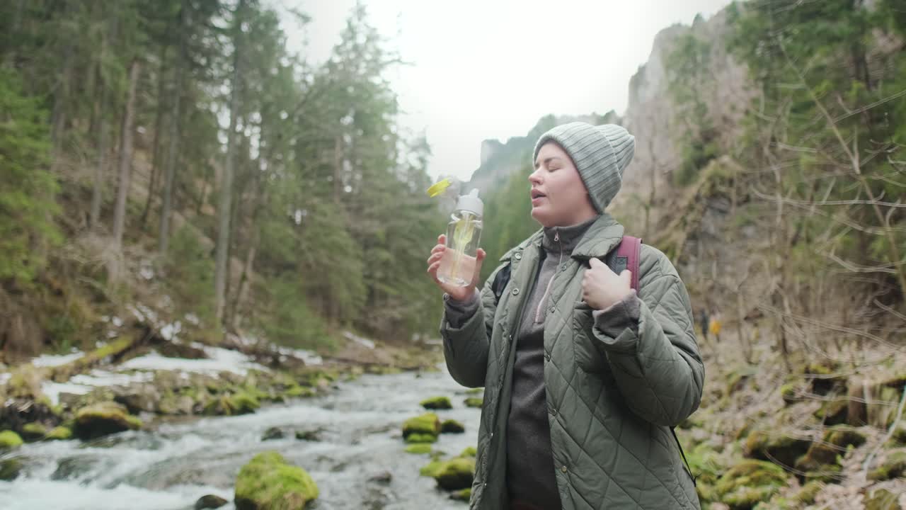 Woman Hiking and Drinking Water in a Mountain Stream