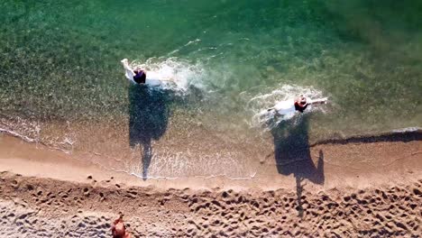 aerial top down shot of horse ride at beach,having fun in clear water in summer