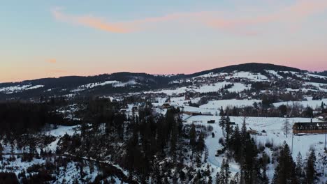 Drone-Aerial-Beautiful-Shot-of-Snow-landscape-with-traditional-Polish-houses-at-sunset