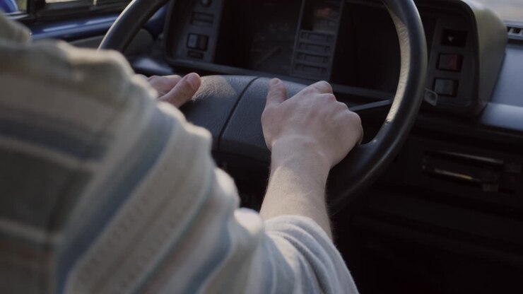 Le mani di un uomo che guida un vecchio camper durante un roadtrip