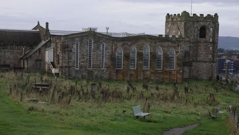 slow panning shot of a historic cemetery on the hillside alongside whitby abbey