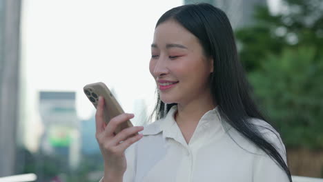 young asian woman using smartphone outdoors in urban setting