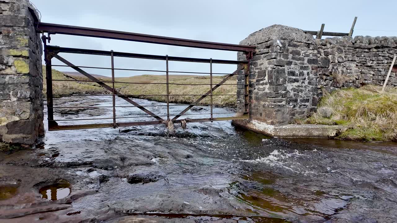 Vandforvaltning og infrastrukturmodstandsdygtighed: Port over Burnhope Reservoir-floden i et landligt landskab, der viser vandstrømskontrol og miljøforvaltning.