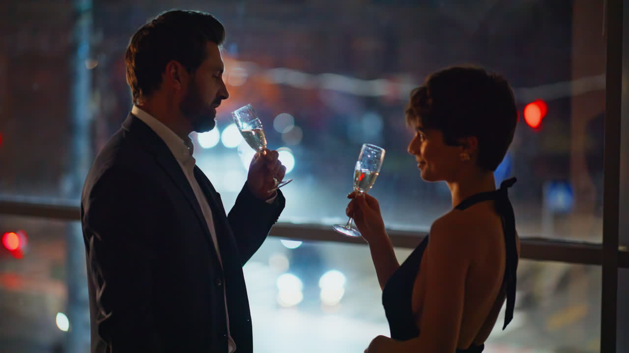 Coppia la sera beve champagne festeggiando l'anniversario, primo piano alla finestra buia