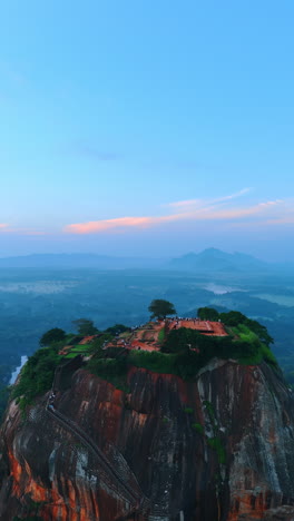 panning view of sigiriya fortress in sri lanka at sunset. hazy view of green landscapes at backdrop. vertical video.