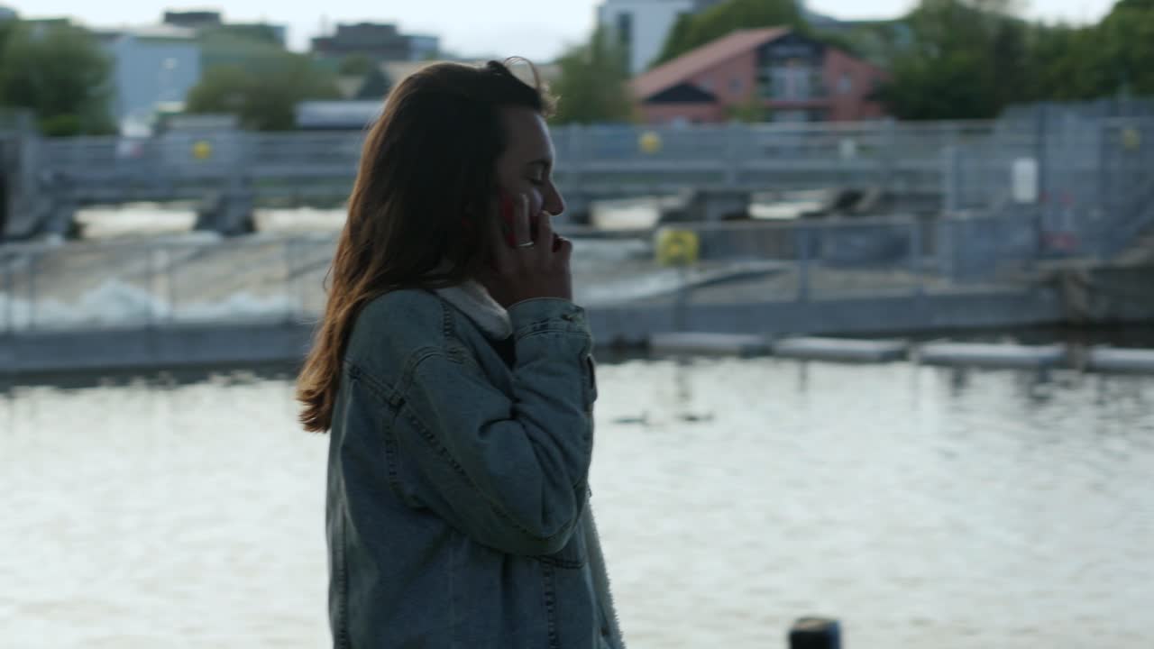 Woman walks along galway ireland canal talking laughing on phone, windy day