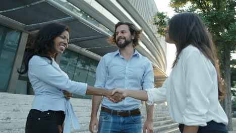 three people shaking hands on background of business center