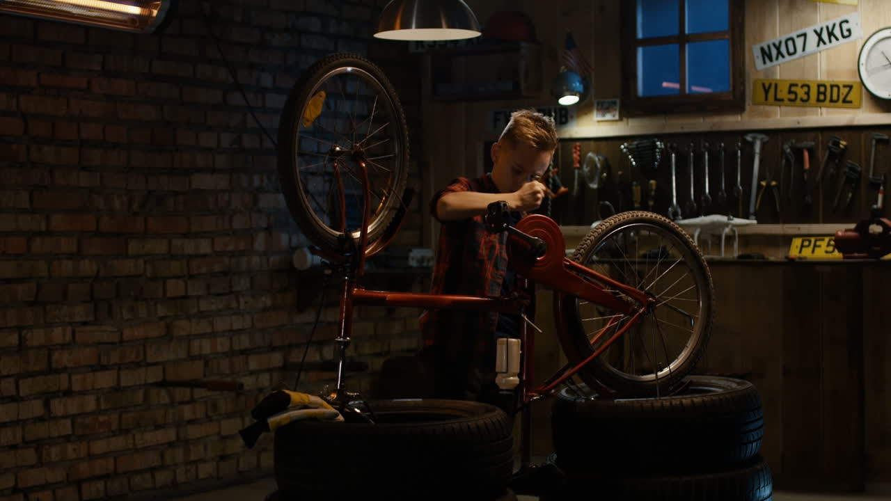 Boy repairing his bike in a garage