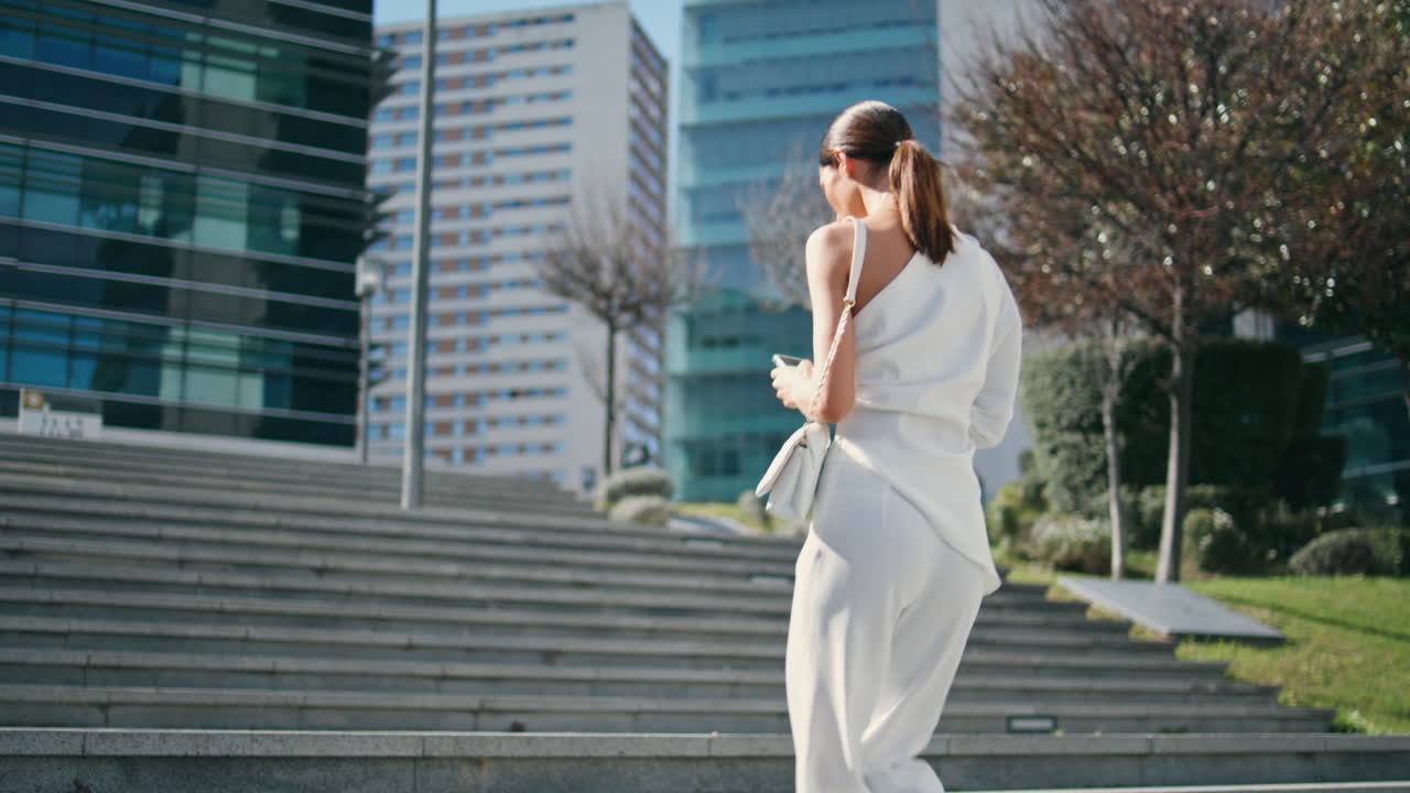 트렌디한 여성이 위층으로 올라가는 도시 공원 드폰을 들고. 치크한 여성이 계단을 고