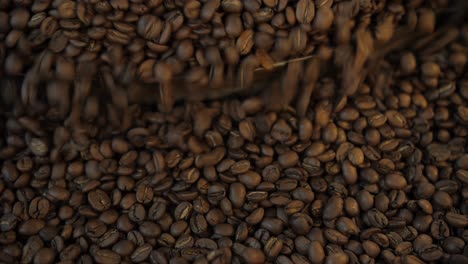 coffee beans mixing on cooling plate after roasting, closeup top down, dark