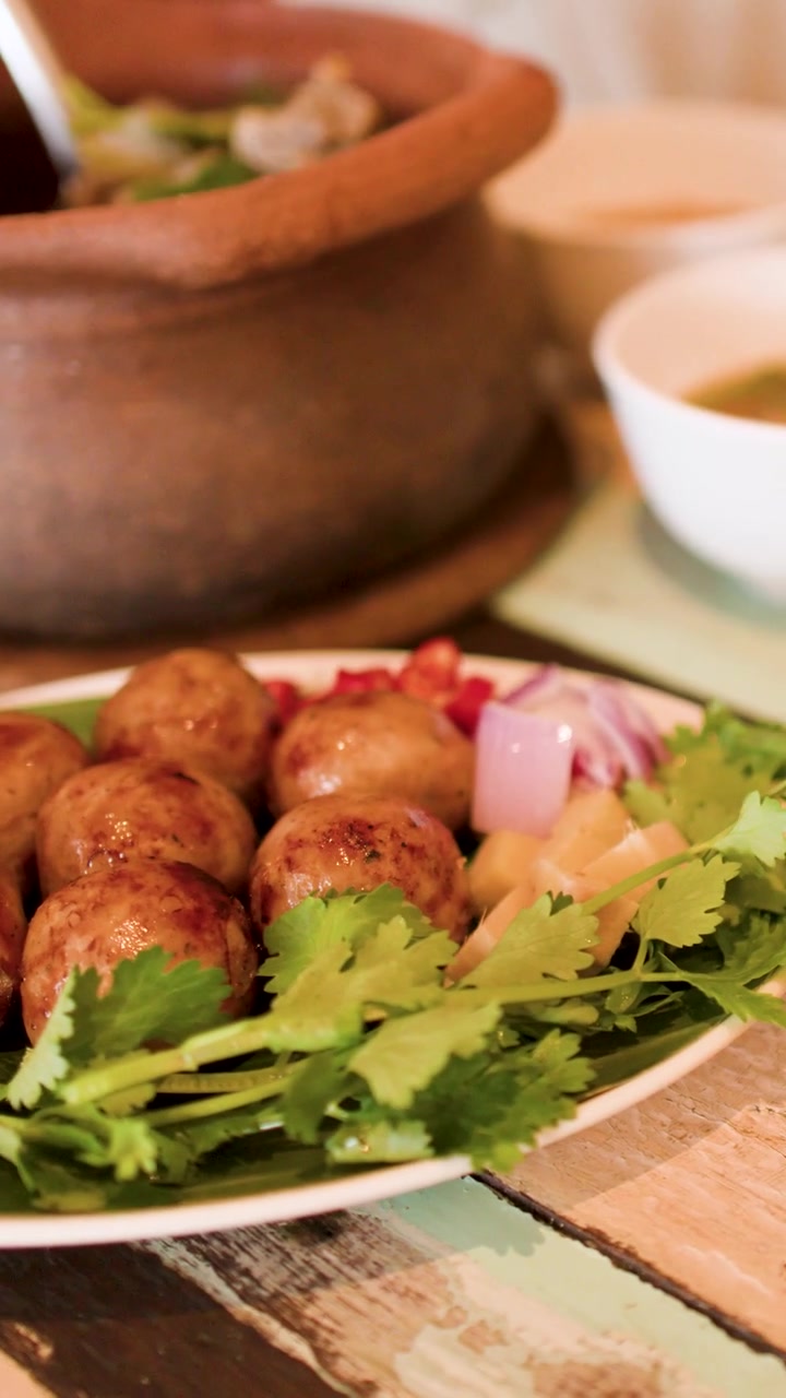 Primo piano di autentico cibo Isan con zuppa in pentola di terracotta e salsicce alla griglia a Bangkok, Thailandia