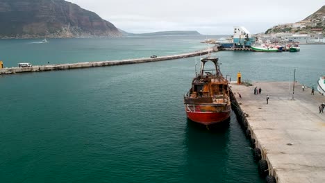 un dron captura una impresionante vista aérea de un viejo y oxidado barco de pesca atracado en un puerto