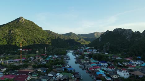 Drone-flying-towards-the-picturesque-landscape-while-the-Bang-Pu-Fishing-Village-is-covered-by-shadows-made-by-the-mountains,-Sam-Roi-Yot-National-Park,-Prachuap-Khiri-Khan,-Thailand