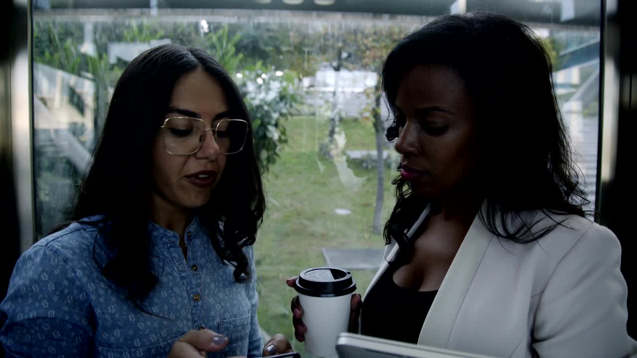 Serious multiethnic businesswomen with gadgets discussing work