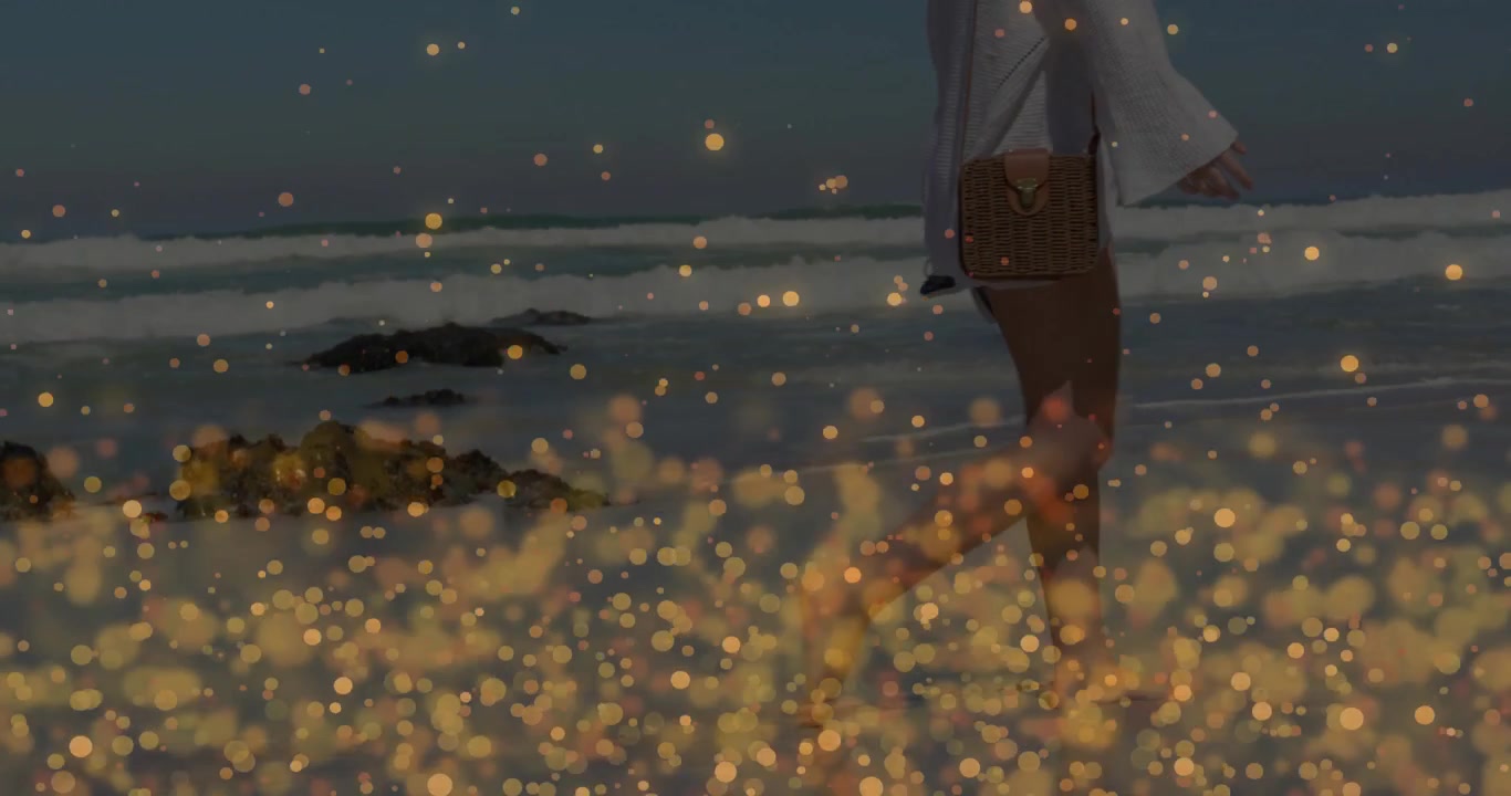 Mujer pisando arena mojada y activando partículas bokeh doradas mientras ilustra un anuncio de viajes.