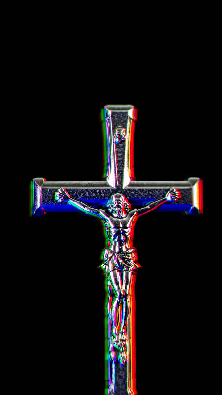 Low-angle video still of a crucifix against a dark background, emphasizing shadows and highlights