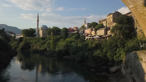 Low-aerial-flight-under-rebuilt-Mostar-old-bridge-over-Neretva-River