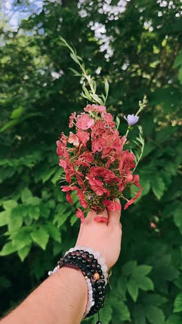 hand holding a bouquet of flowers in a garden